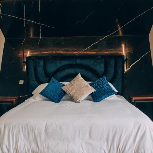 a bed with blue and white pillows on it at Örök Hotel in Rionegro