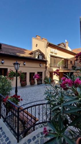 a building with a balcony and a courtyard with flowers at Red Lion Pub & Apartments Szentendre in Szentendre