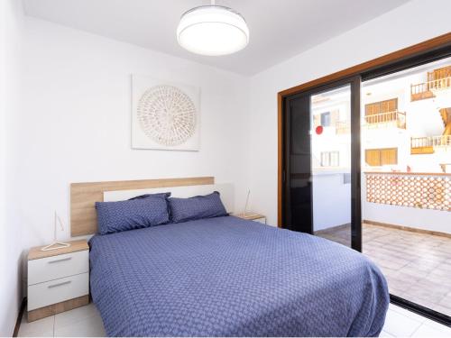 a bedroom with a bed with a blue comforter at Live cardon las americas con piscina y terraza in Arona