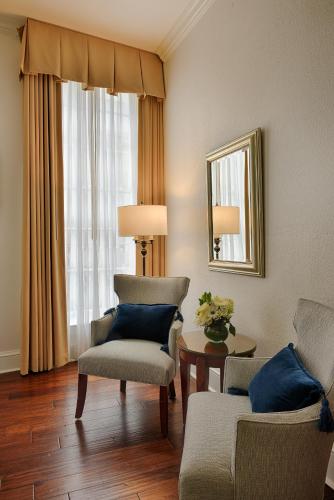 a living room with two chairs and a table and a mirror at voco St James Hotel by IHG in New Orleans