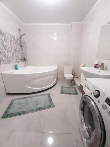 ein Badezimmer mit einer Badewanne und einer Waschmaschine. in der Unterkunft Comfortable apartment in Bischkek