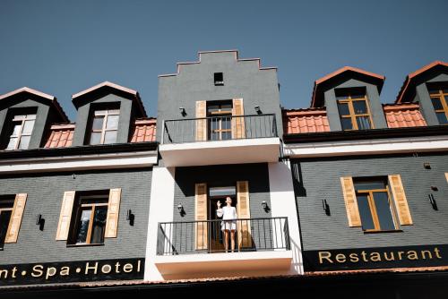 un hombre parado en el balcón de un hotel spa en Hotel Dynasty, en Kamianets-Podilskyi