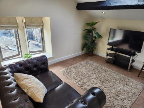a living room with a leather couch and a flat screen tv at The Garden Bar Rooms in Baildon