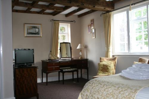 a bedroom with a bed and a dresser with a mirror at The Manor Guest House in Linton on Ouse
