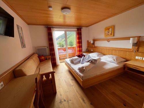 a bedroom with a bed and a couch and a window at Montanara Apartment & Zimmer in Ramsau am Dachstein