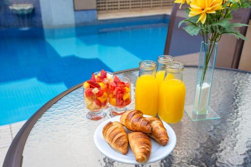 a table with a plate of croissants and fruit and juice at Mercure Sao Paulo JK in Sao Paulo
