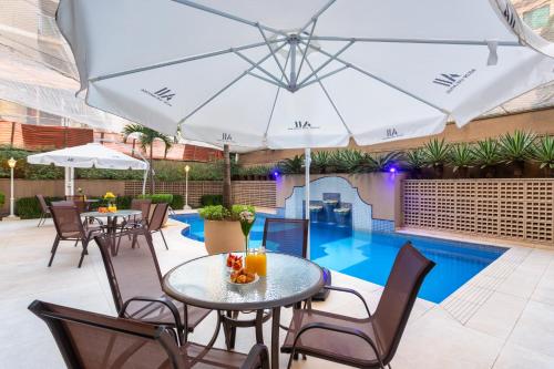 a patio with tables and chairs and a pool at Mercure Sao Paulo JK in Sao Paulo