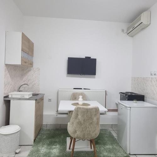 a room with a table and a chair and a sink at Family Apartmani Le in Leskovac