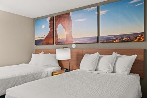 a hotel room with two beds and a painting on the wall at Days-Inn by Wyndham Albuquerque I-25 in Albuquerque