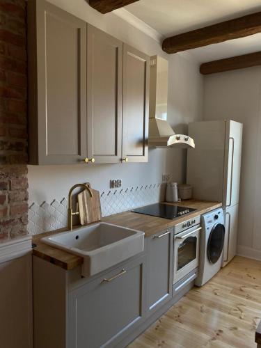 a kitchen with white cabinets and a sink and a dishwasher at Apartments PSD Anny Łajming 3A in Słupsk