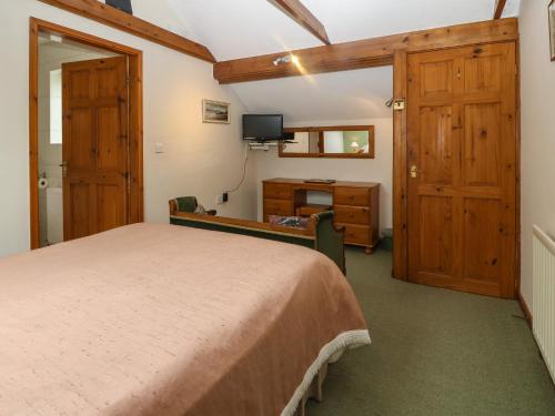 The Cottage at Ty Newydd في لانفيربولوغووِنشِل: غرفة نوم بسرير ومكتب وتلفزيون
