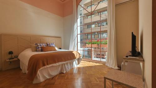 een slaapkamer met een bed en een groot raam bij Casa Par Grand Suites in Buenos Aires