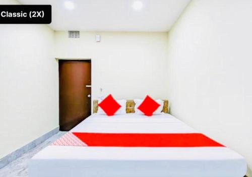 ein Schlafzimmer mit einem großen weißen Bett mit roten Kissen in der Unterkunft Hotel Somnath Guest House ! Puri in Puri