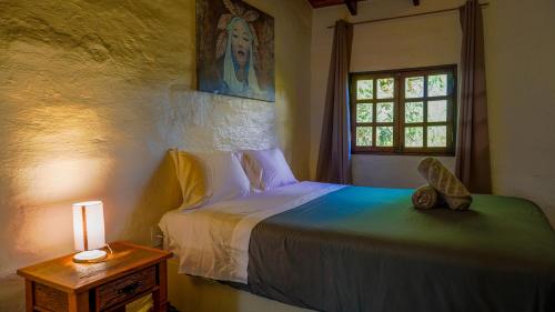 a bedroom with a bed and a window and a lamp at Terra Coral - Chapada dos Veadeiros in Alto Paraíso de Goiás