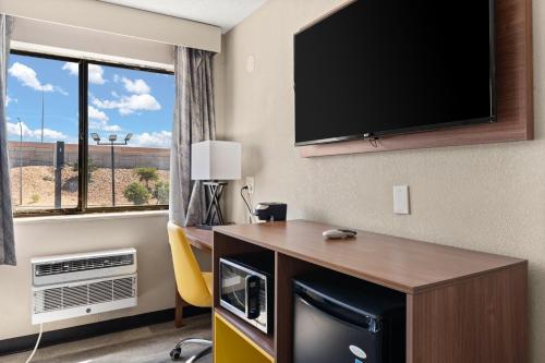 a hotel room with a desk with a television on the wall at Days-Inn by Wyndham Albuquerque I-25 in Albuquerque