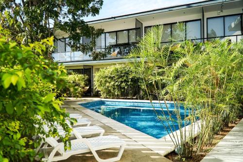 a swimming pool in front of a house with two lawn chairs at Deluxe Apartments Azure in Bacalar