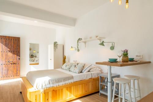 a bedroom with a bed and a table and stools at Casa La Fontana 2 in Vejer de la Frontera