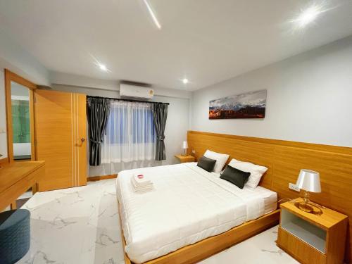 Un dormitorio con una gran cama blanca y una ventana en Pattaya Aqua Villa - Pool - Kitchen - BBQ - Smart TV en Pattaya South