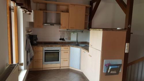 a small kitchen with wooden cabinets and appliances at Ferienhaus Am Stadtpark in Ballenstedt