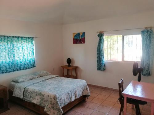 a bedroom with a bed and a desk and two windows at Casa Las Animas in El Carmen