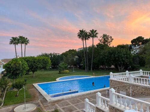 a large swimming pool in a yard with palm trees at Duplex in residential complex with pool in Altea