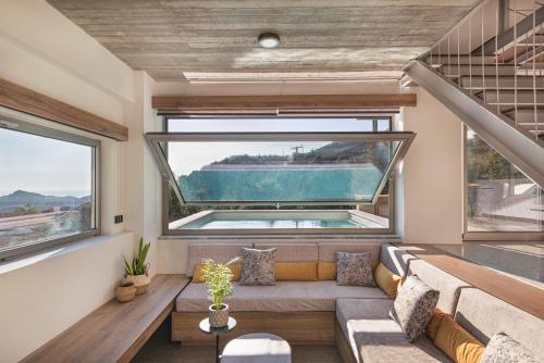 Una sala de estar con un sofá y una ventana grande. en New Modern Villa Domus Rodia with private pool & BBQ, 4km from nearest beach, en Marioú