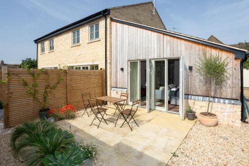 a patio with chairs and a table in front of a house at Harpers Yard - 30 Chipping Norton in Chipping Norton