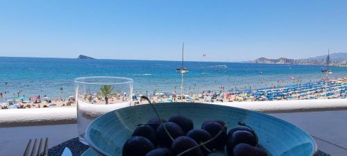 a bowl of food and a glass of water and a beach at Principado Benidorm Suites Levante in Benidorm