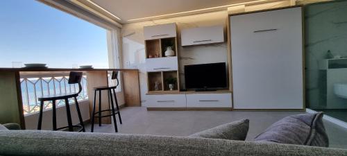 a living room with a couch and a tv at Principado Benidorm Suites Levante in Benidorm