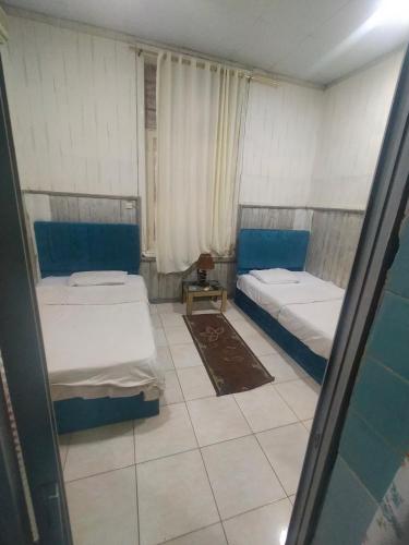 Habitación pequeña con 2 camas y espejo. en my hotel en Al Minya