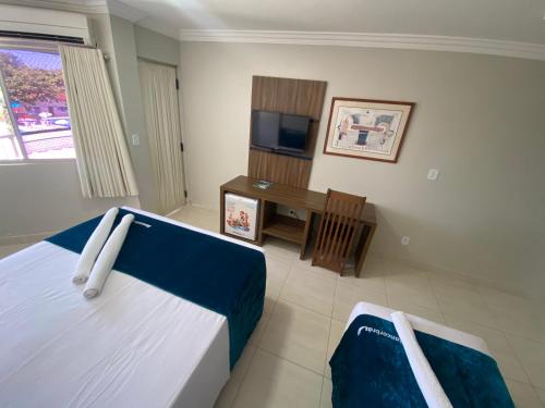 a bedroom with a bed and a desk and a television at Império Romano Caldas Novas com piscinas 24h, e diRoma Acqua Park e Splash in Caldas Novas