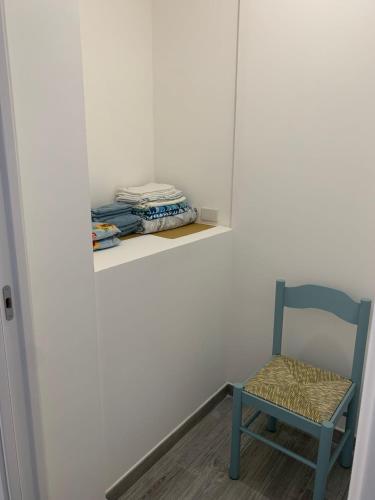 einem blauen Stuhl neben einer Wand mit einem Regal in der Unterkunft La coccinella rooms in Milazzo