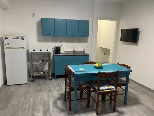 eine Küche mit einem blauen Tisch und Stühlen sowie einem Kühlschrank in der Unterkunft La coccinella rooms in Milazzo