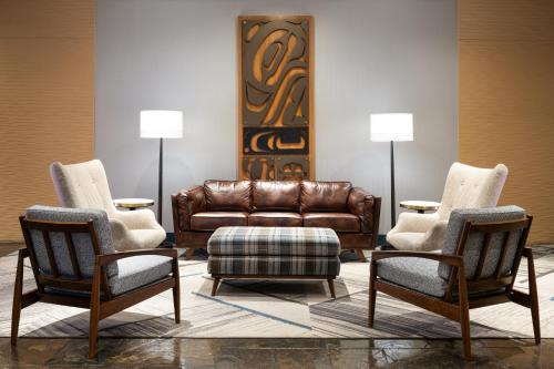 a living room with a leather couch and two chairs at Four Points by Sheraton Victoria Gateway in Victoria