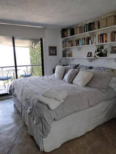 a large white bed in a room with bookshelves at Habitación con vista al lago in Valle de Bravo