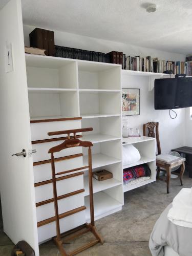 a room with white shelves and a tv at Habitación con vista al lago in Valle de Bravo