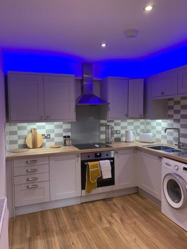 cocina con armarios blancos y techo azul en Barchester House Apartment Standard, en Salisbury