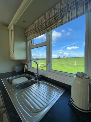 a kitchen sink with a window with a view of a field at East kitcham lodge in Launceston