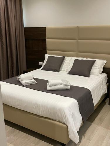 ein großes Bett mit weißer Bettwäsche und schwarzen Kissen in der Unterkunft HotelLuxuryPrato in Prato