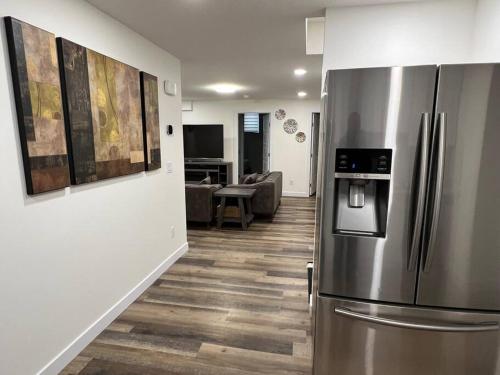 a kitchen with a stainless steel refrigerator and a living room at Modern Suite by Spruce Meadows in Calgary
