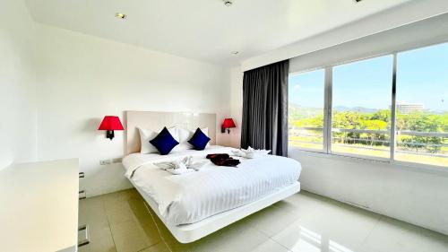 Un dormitorio blanco con una gran cama blanca con almohadas azules. en Grand Sunset Hotel Phuket, en Karon Beach