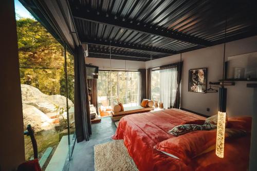 um quarto com uma cama grande e uma janela grande em Cabana Secreta em Petrópolis