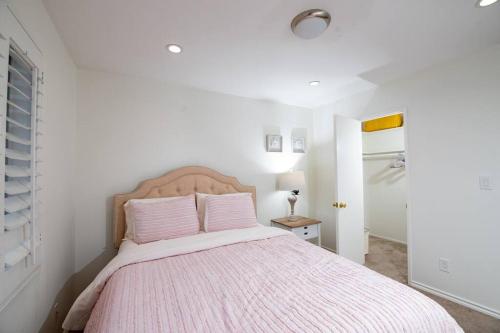 a white bedroom with a large bed with pink sheets at Brand New Remodeled 3 Bedroom Home in Reseda in Los Angeles
