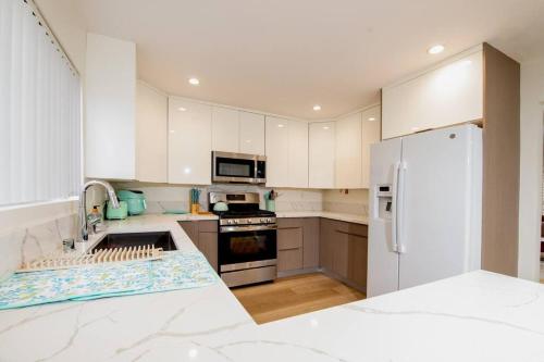 a kitchen with white cabinets and a white refrigerator at Brand New Remodeled 3 Bedroom Home in Reseda in Los Angeles