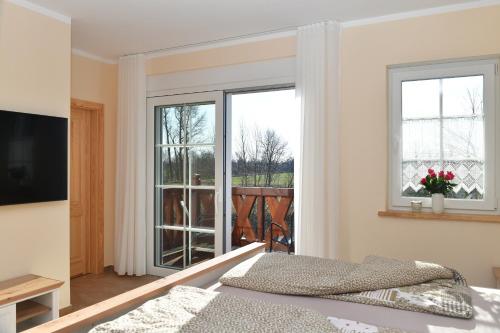 Schlafzimmer mit einem Bett und Blick auf einen Balkon in der Unterkunft Gasthaus Bukoitza in Radensdorf