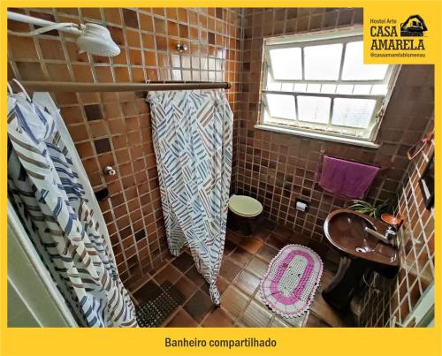 a tiled bathroom with a toilet and a window at Casa Amarela Blumenau Hospedagem Alternativa in Blumenau