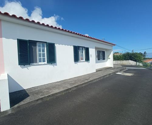 uma casa branca com persianas verdes numa rua em OCEANVIEW em Lajes das Flores