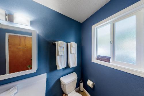 ein blaues Bad mit einem WC und einem Fenster in der Unterkunft Hale Kai in Keaau