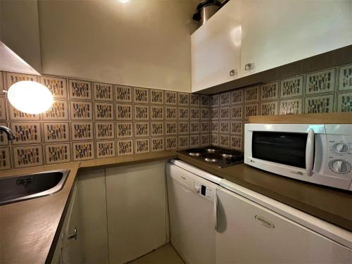 une cuisine avec un micro-ondes et un plan de travail dans l'établissement Studio cosy 4 pers avec balcon sud, skis aux pieds à Reberty 1850 - FR-1-452-44, aux Menuires