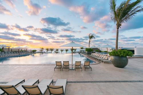 a resort with a pool and chairs and palm trees at Seadust Cancun Family Resort - All Inclusive in Cancún